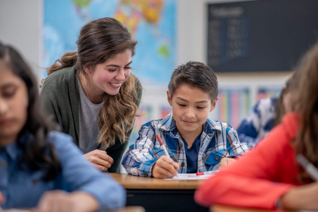 Teacher helping student at desk